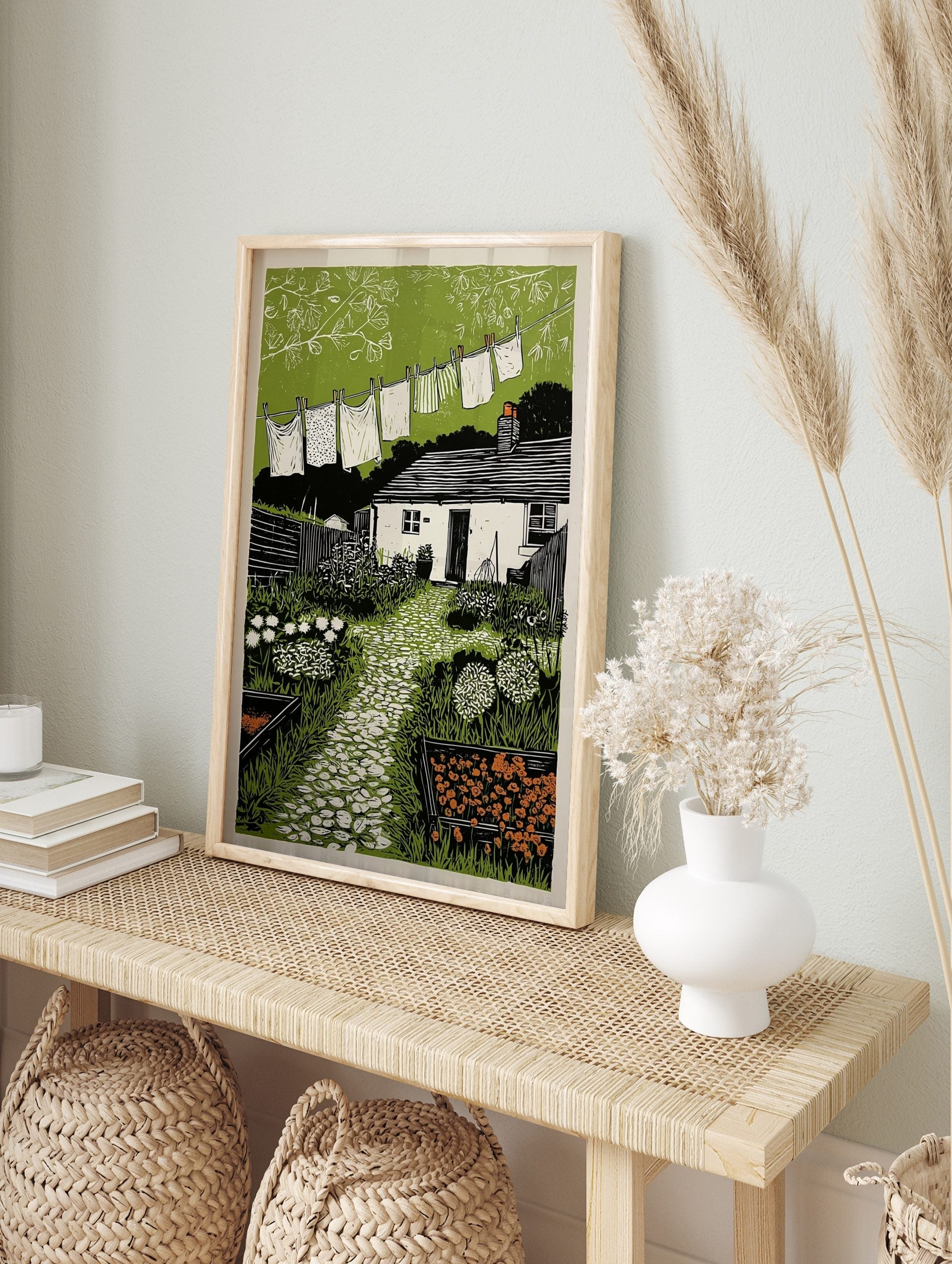 Cottage garden art print with clothesline, paved path, white cottage, and green foliage, in an alternate framed mockup