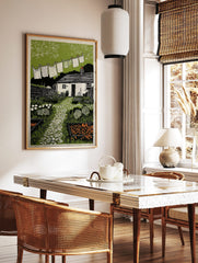 Cottage garden art print with clothesline, paved path, white cottage, and green foliage, in a styled room mockup