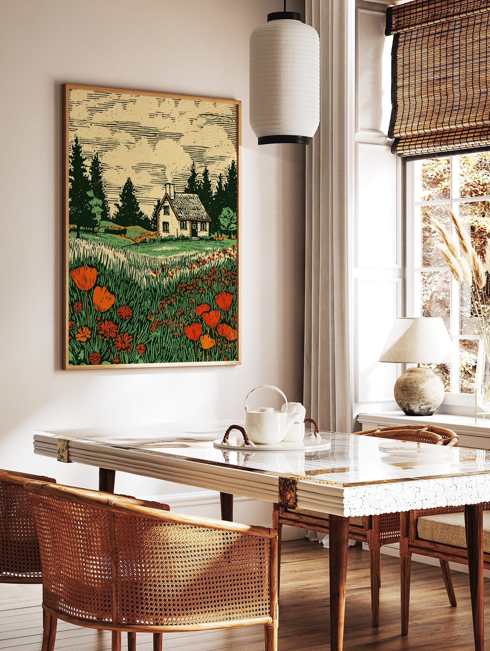 Woodcut print of a white cottage in a field of red poppies and tall green grass with pine trees, in a styled room mockup