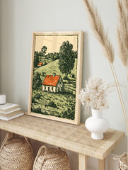 Woodcut style print of a white farmhouse with a red roof in a green, hilly countryside, in an alternate framed mockup
