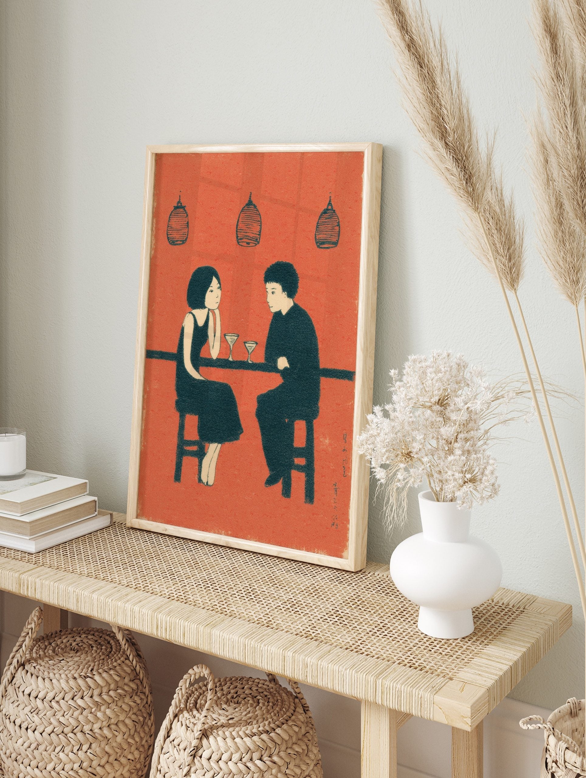 Illustrative wall art print of a couple at a bar with martini glasses, in an orange, black, in an alternate framed mockup