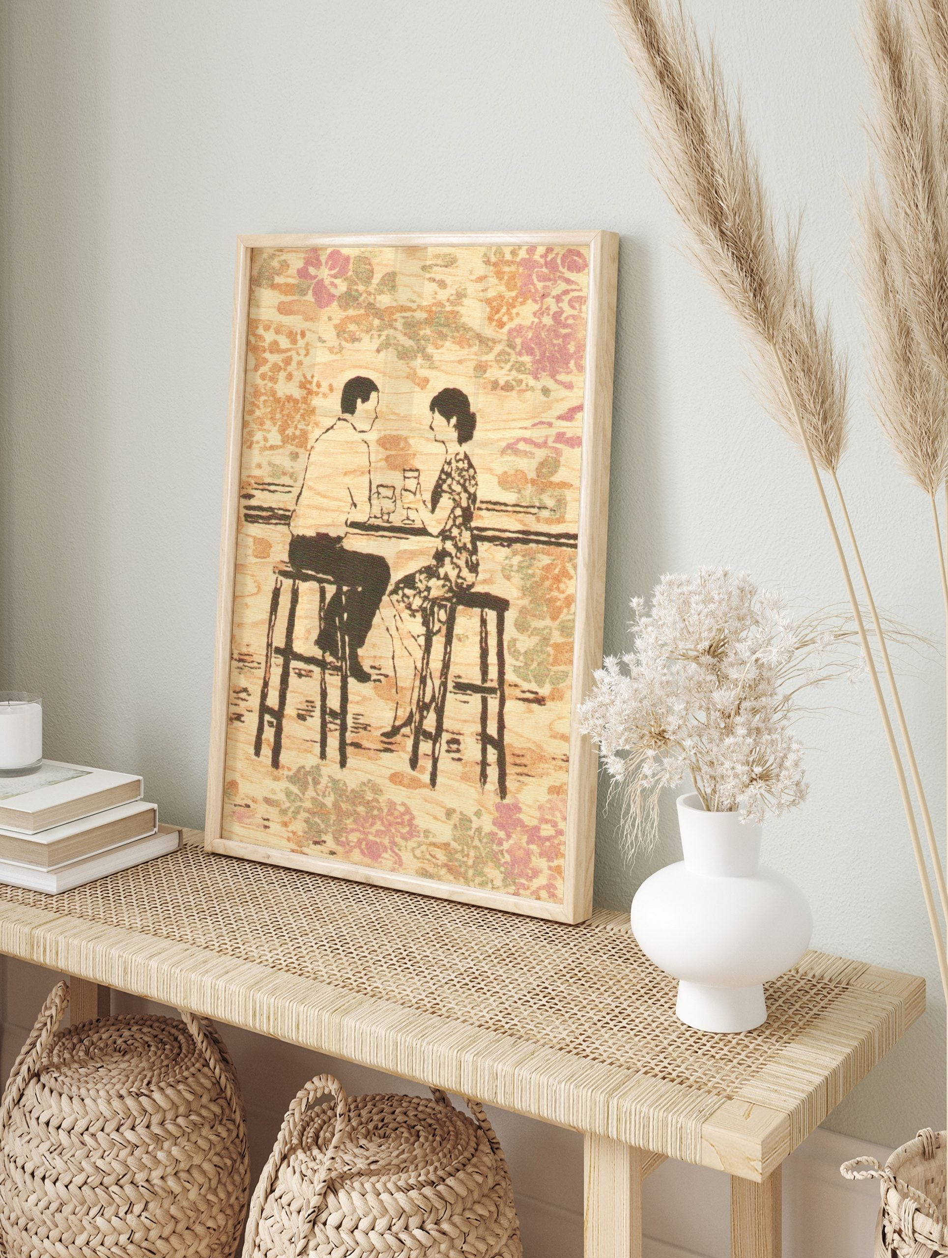Illustrative print of a couple at a bar, holding drinks, against a wood-grain and floral, in an alternate framed mockup
