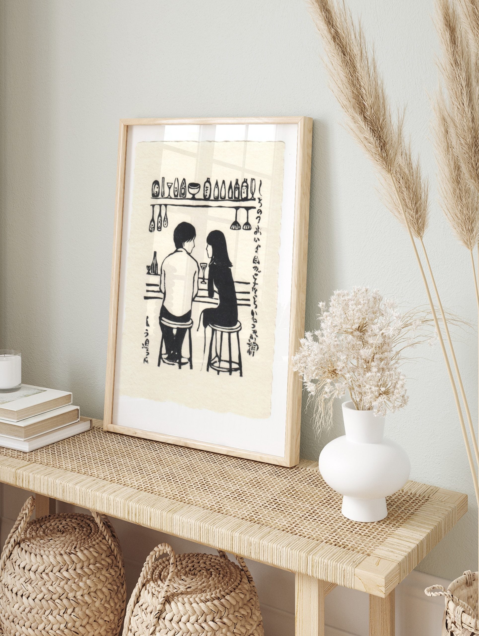 Monochrome illustration of a couple at a bar with bottles, glasses, and Japanese text on a, in an alternate framed mockup