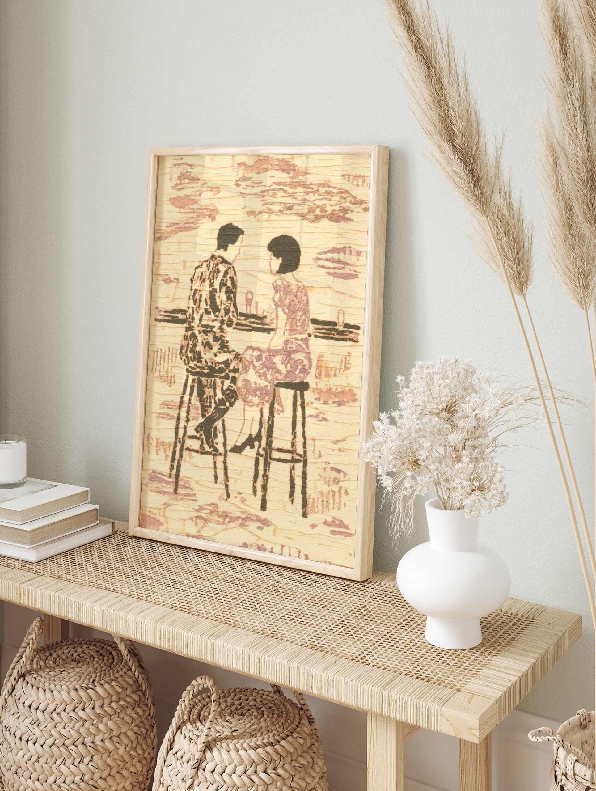 Textured illustrative print of a couple on bar stools at a counter, in muted beige and purple, in an alternate framed mockup