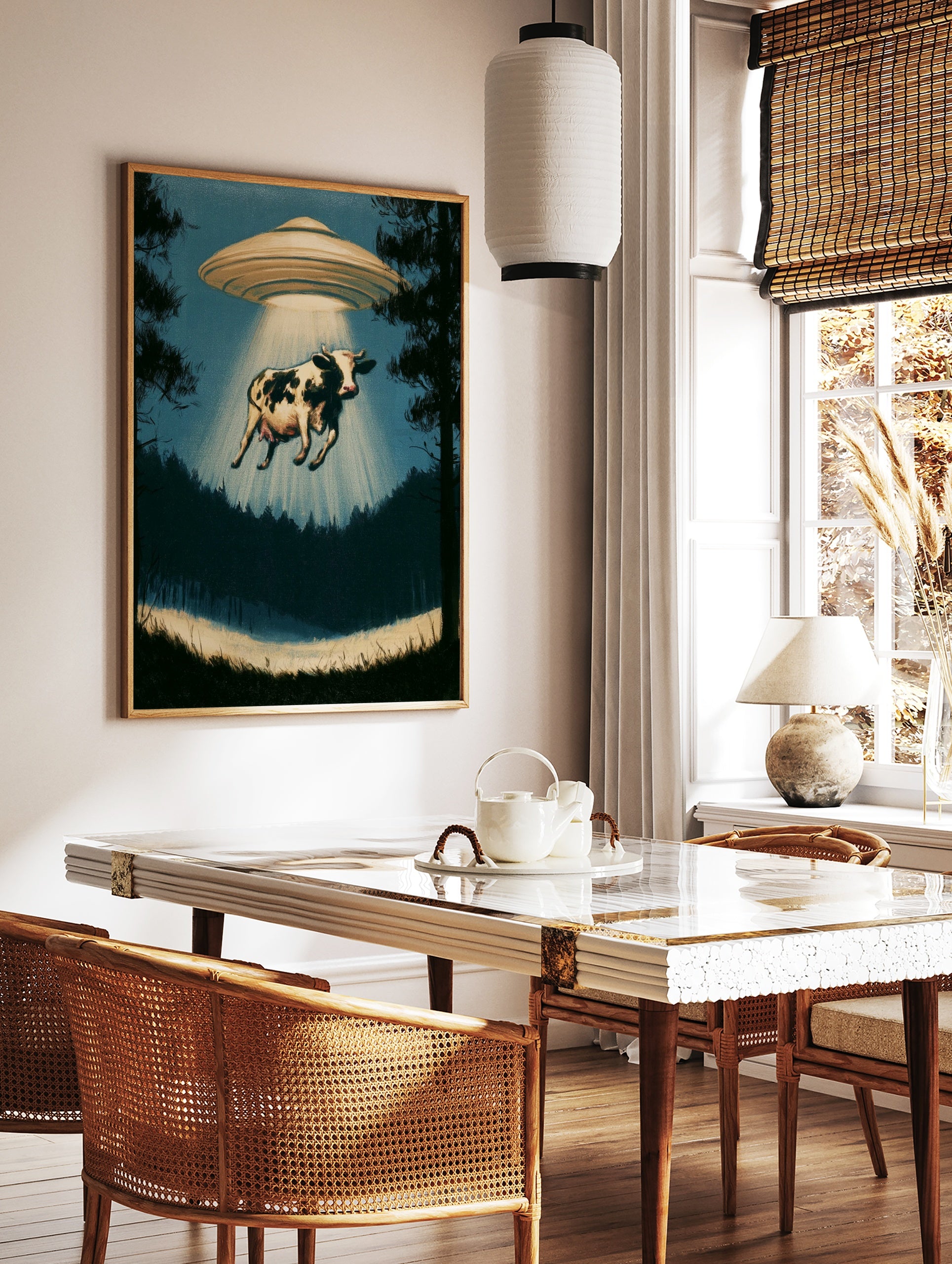 Surreal cow abduction wall art print featuring a UFO in a silhouetted forest with a glowing, in a styled room mockup