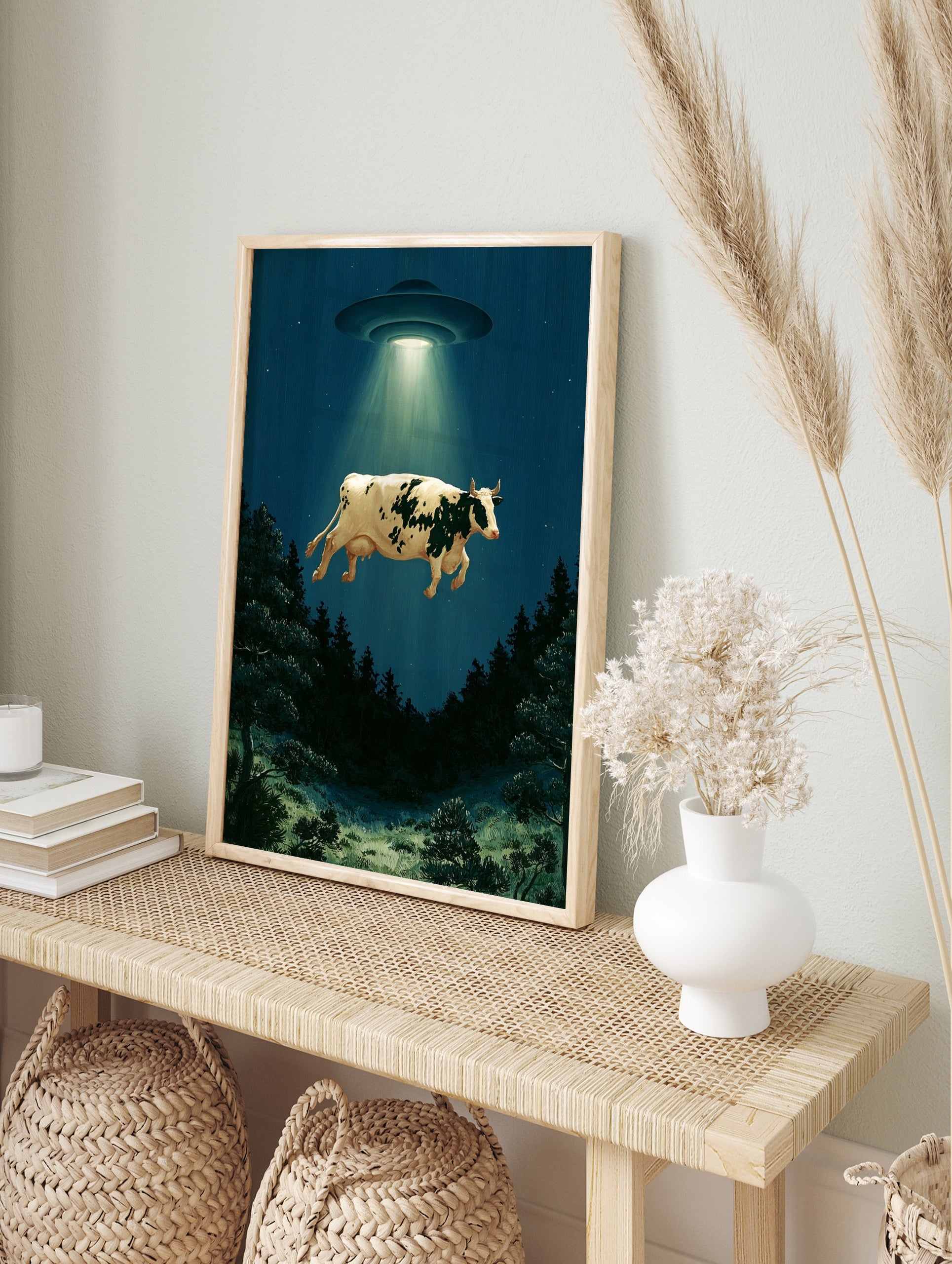 Surreal cow abduction wall art print featuring a UFO lifting a cow above a dark forest at, in an alternate framed mockup
