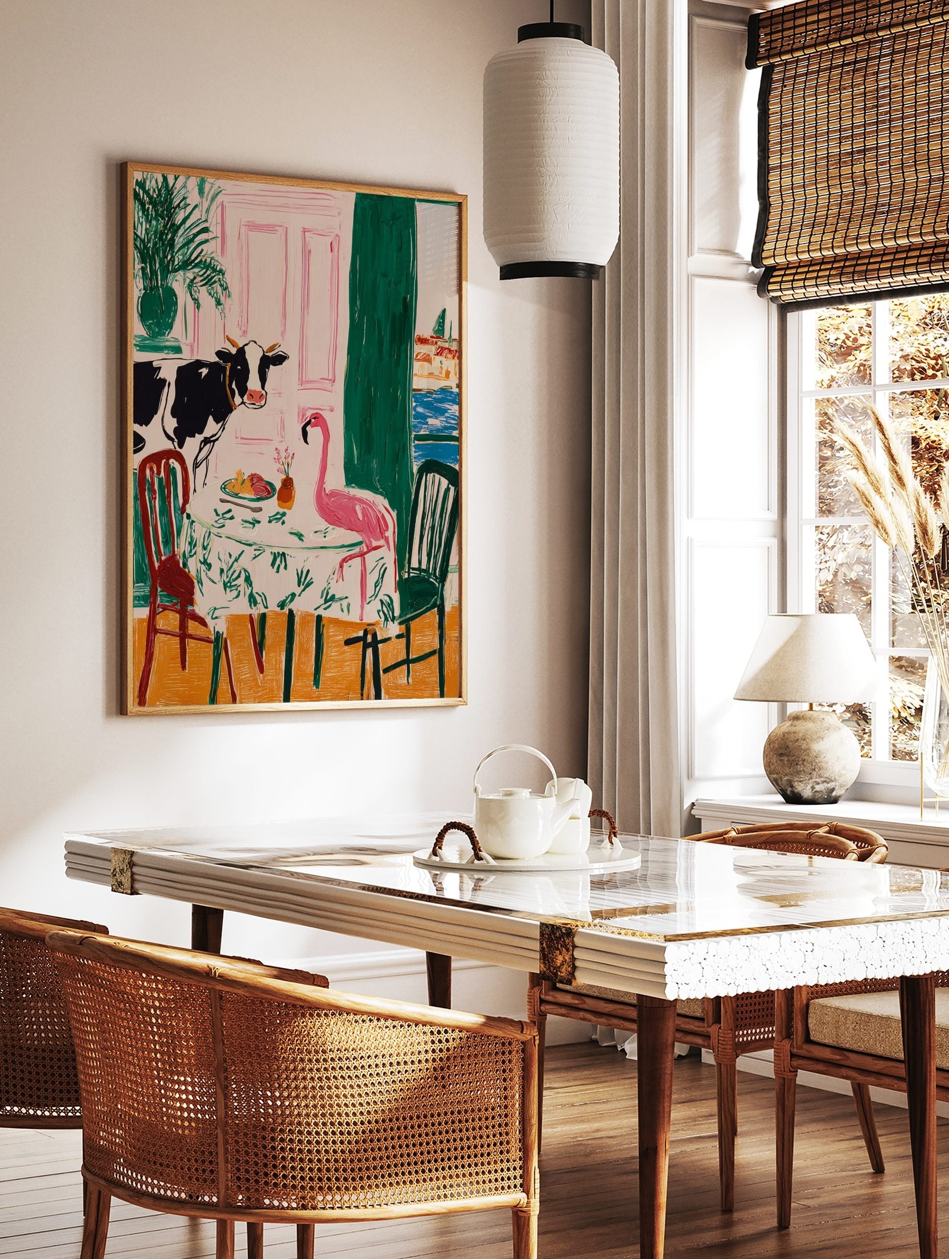 Illustrative wall art of a cow and a pink flamingo dining at a table, with a pink door and cityscape, in a styled room mockup