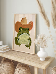 Green frog wearing a brown cowboy hat in a painterly illustrative style art print, in an alternate framed mockup