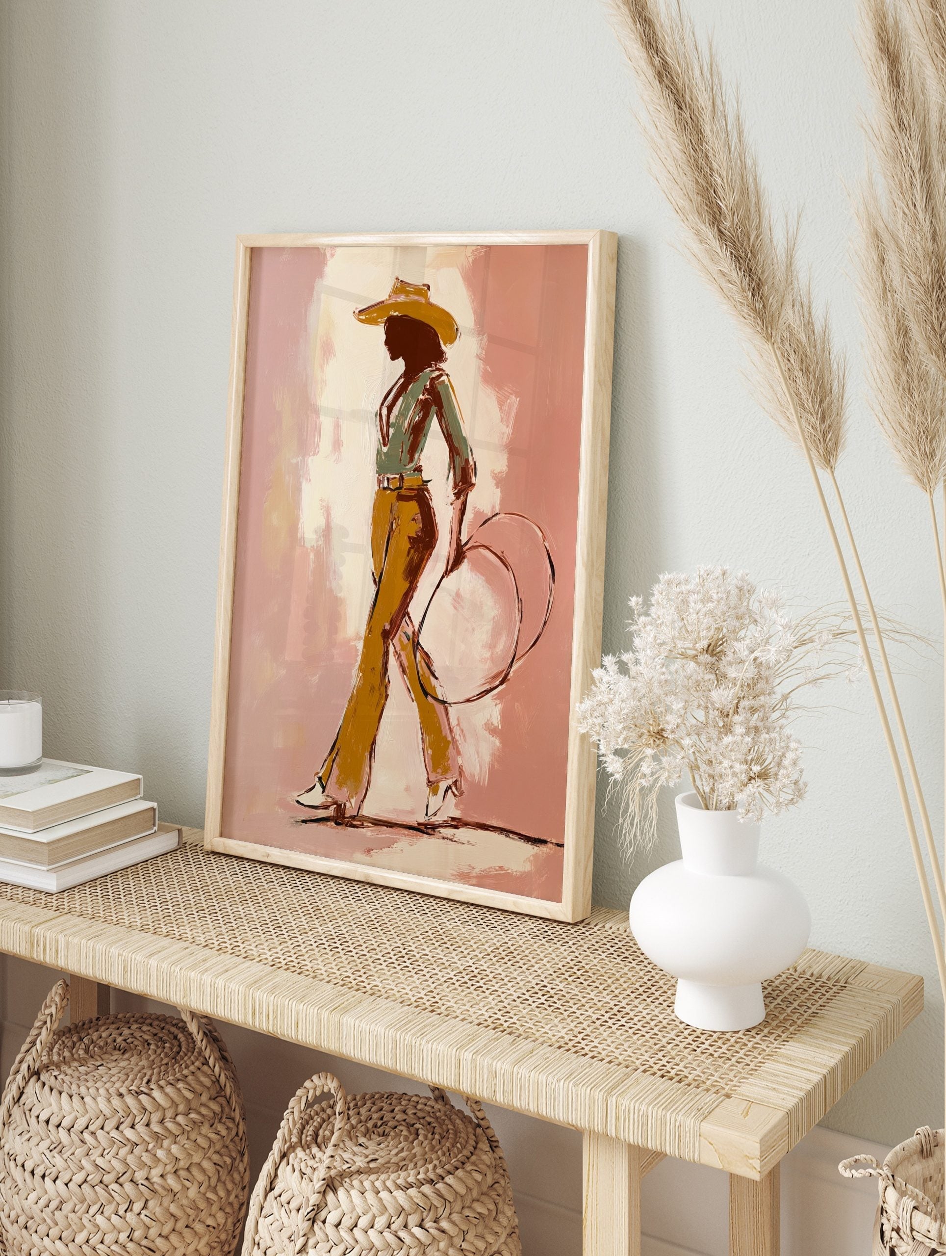 Illustrative cowgirl silhouette art print in a hat, green shirt, ochre trousers, holding a, in an alternate framed mockup