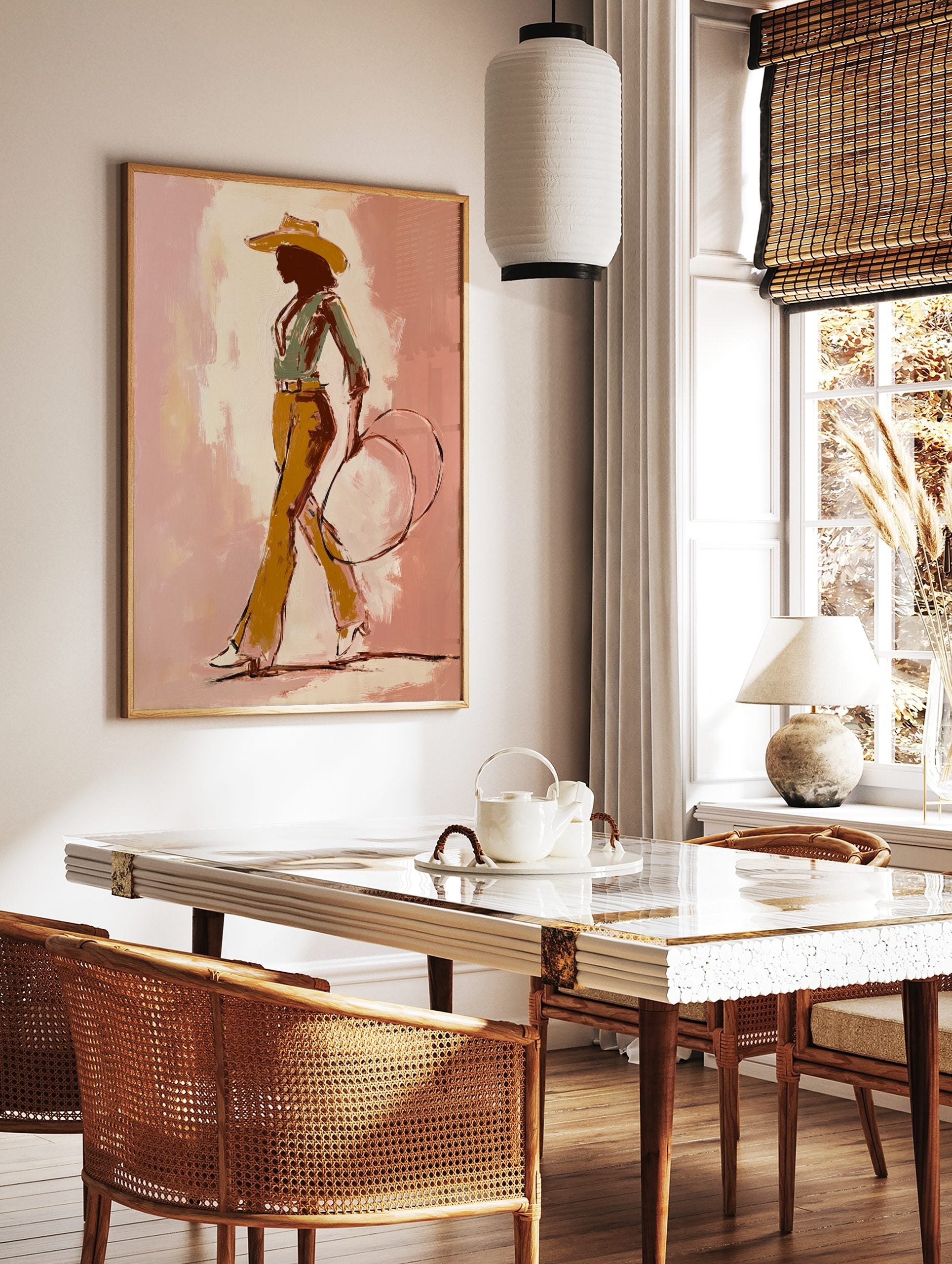 Illustrative cowgirl silhouette art print in a hat, green shirt, ochre trousers, holding a lasso, in a styled room mockup