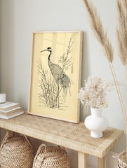 Japanese illustrative print of a crane bird standing in tall grass with a flowering branch on, in an alternate framed mockup