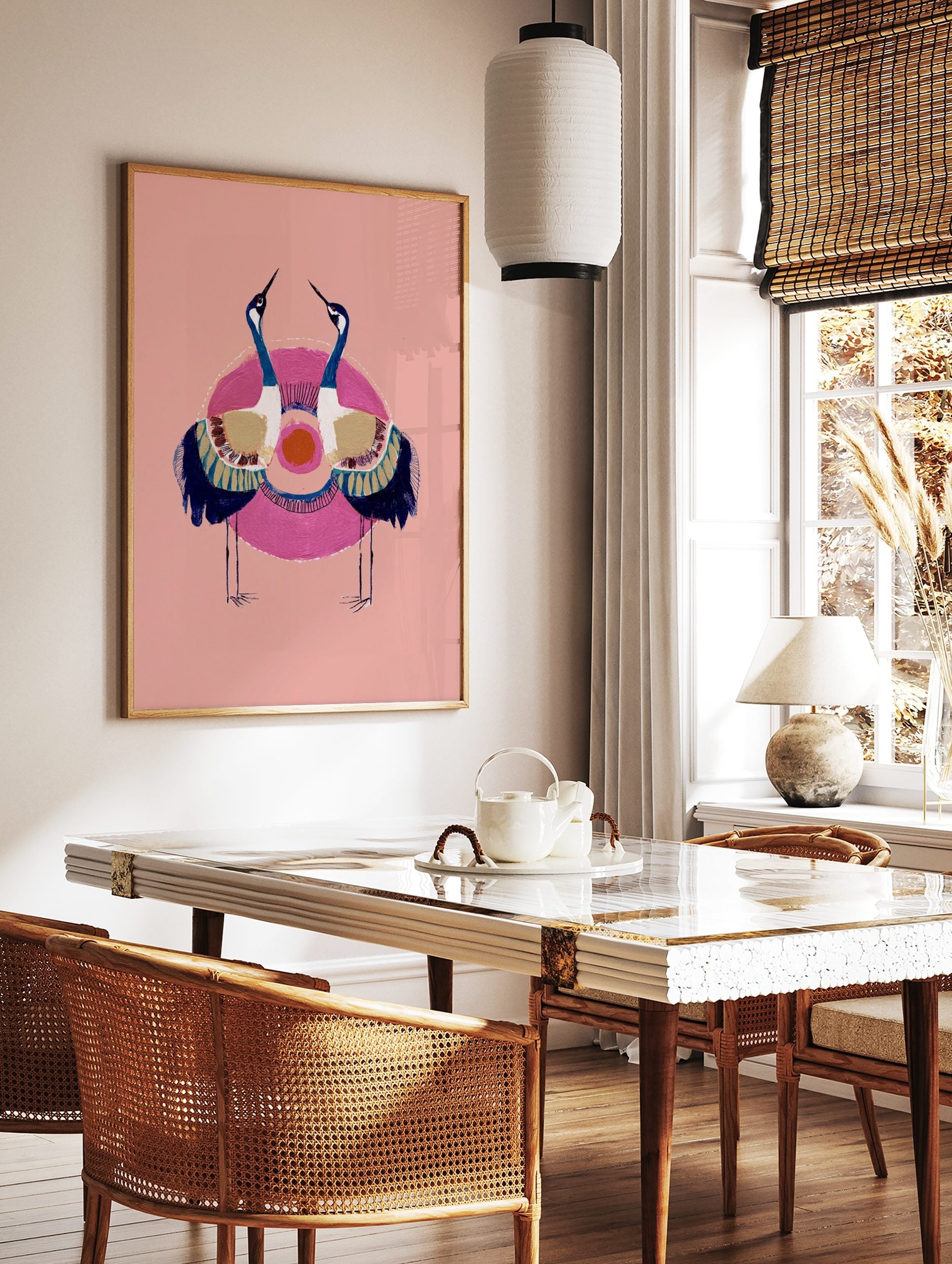 Illustrative crane wall art with two blue and white birds, golden wings, pink circle, orange sun on, in a styled room mockup