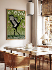 Black and white crane with widespread wings walking through green reeds and thistle plants in, in a styled room mockup