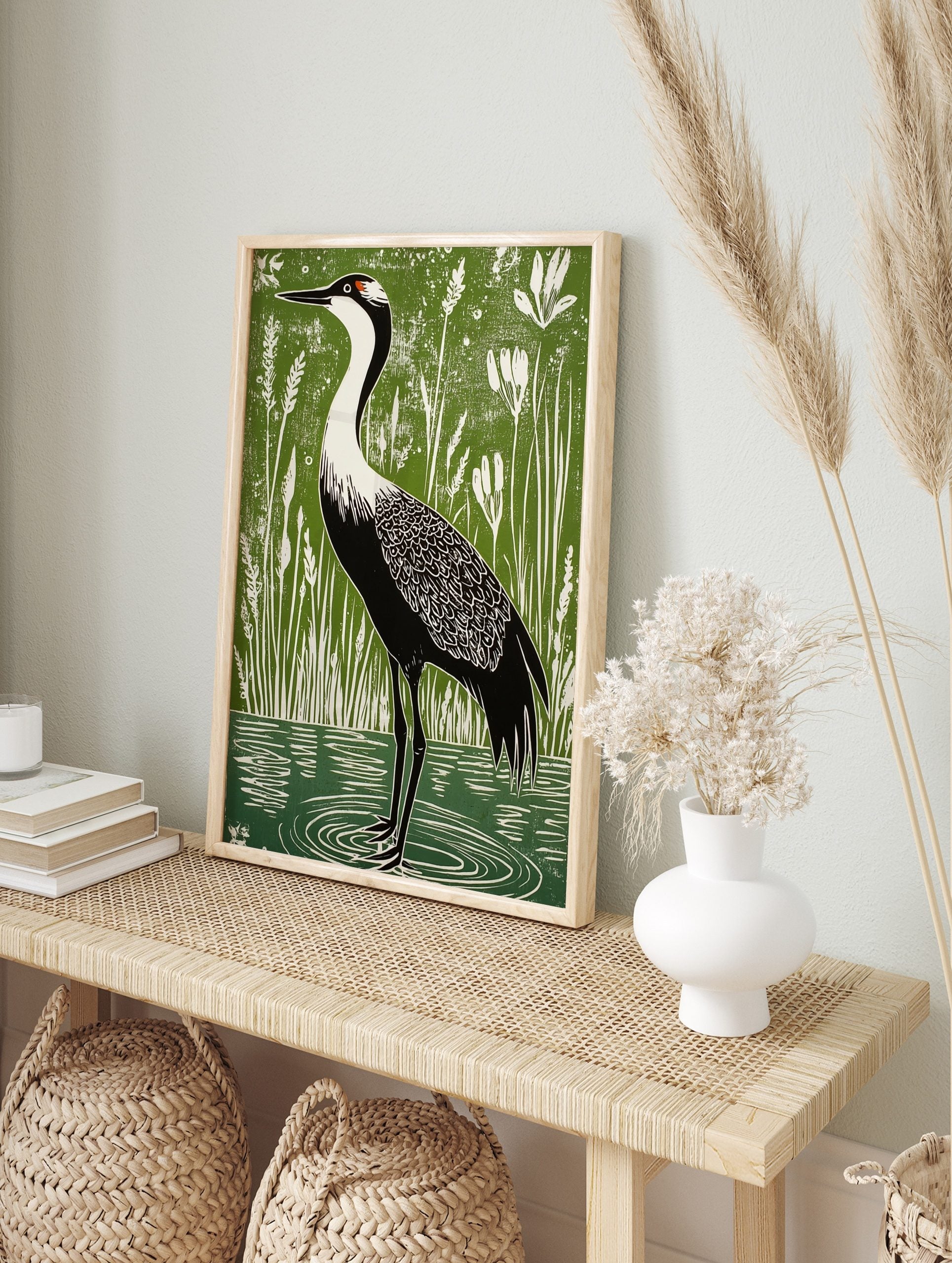 Linocut-style art print of a black and white crane with red head patch in green wetland with, in an alternate framed mockup
