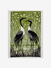Linocut-style print of two black and white cranes in a green marsh with white hearts and reeds