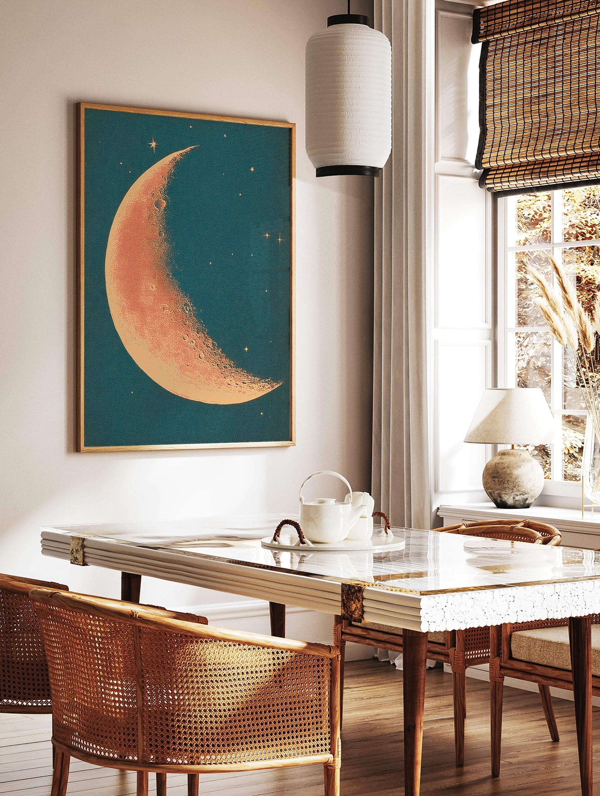 Crescent moon illustration with stippled orange-red surface and cream edge against a deep teal, in a styled room mockup