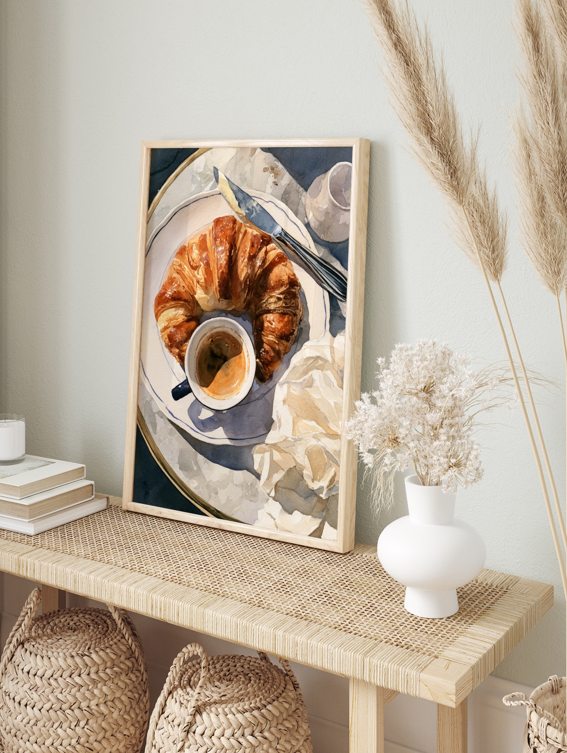 Watercolor illustration of a croissant, coffee cup, and butter knife on a plate, breakfast, in an alternate framed mockup