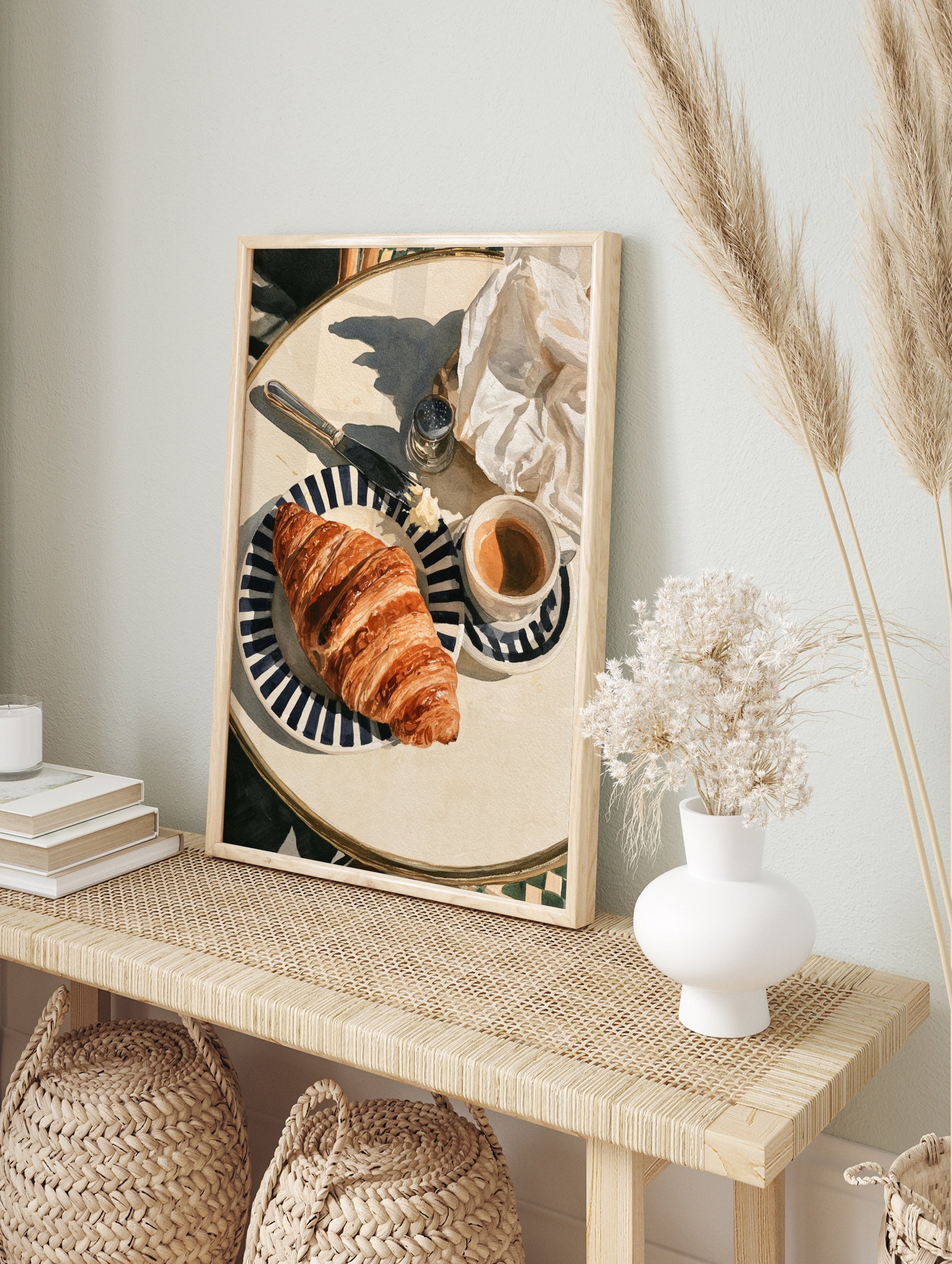 Watercolor-style illustration of a croissant on a striped plate with coffee and a knife, in an alternate framed mockup