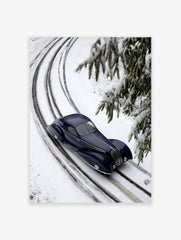 Dark blue vintage streamlined car on snow-covered railway tracks with fir branches in winter