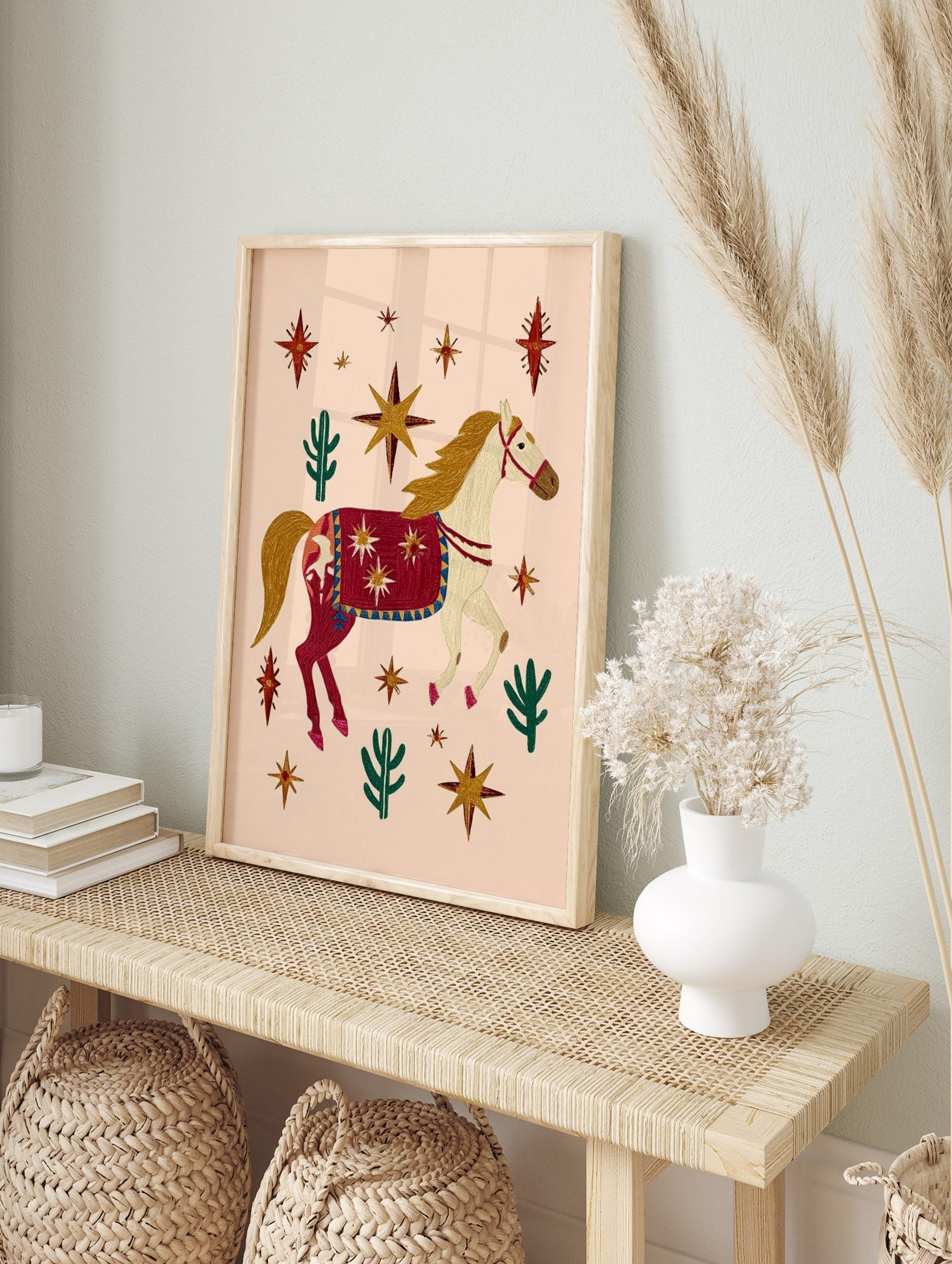 Illustrative decorated horse with red blanket, gold stars, and green cacti on a peach, in an alternate framed mockup