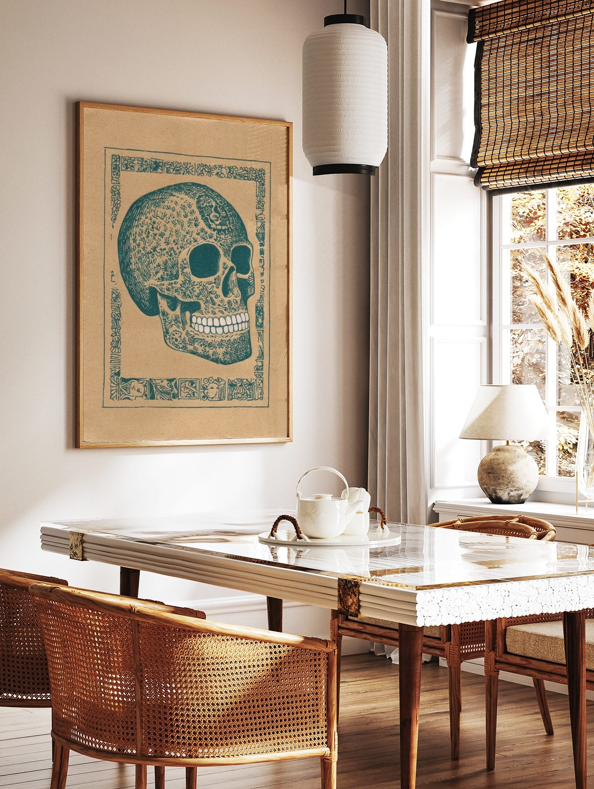 Decorated skull art print with intricate teal patterns on brown paper, framed by an ornate border, in a styled room mockup