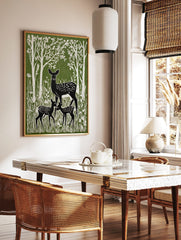 Green and white linocut style print of a mother deer and two fawns in a forest with tall trees, in a styled room mockup