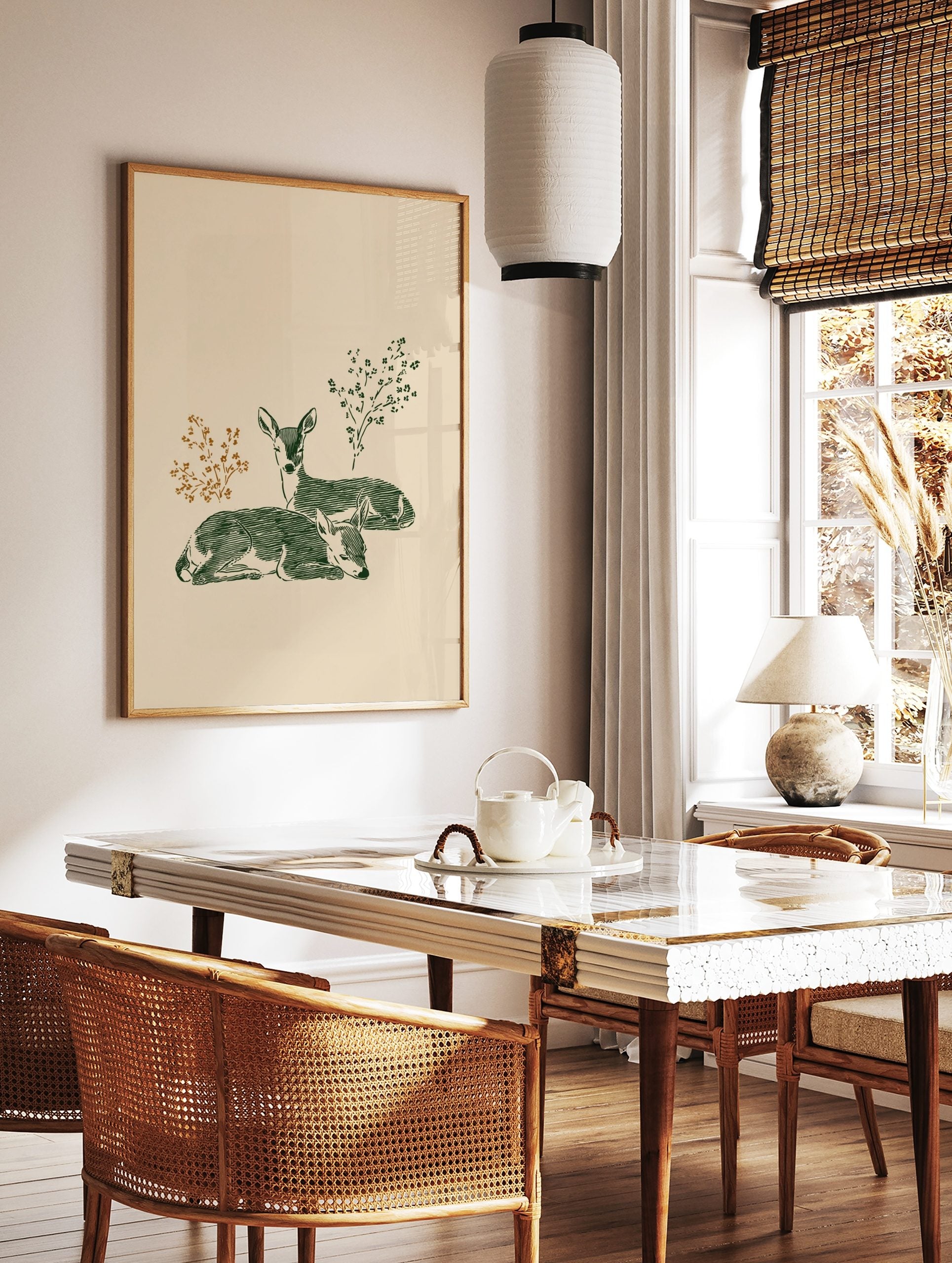 Illustrative print of two green deer fawns resting, with brown and green foliage on a light beige, in a styled room mockup