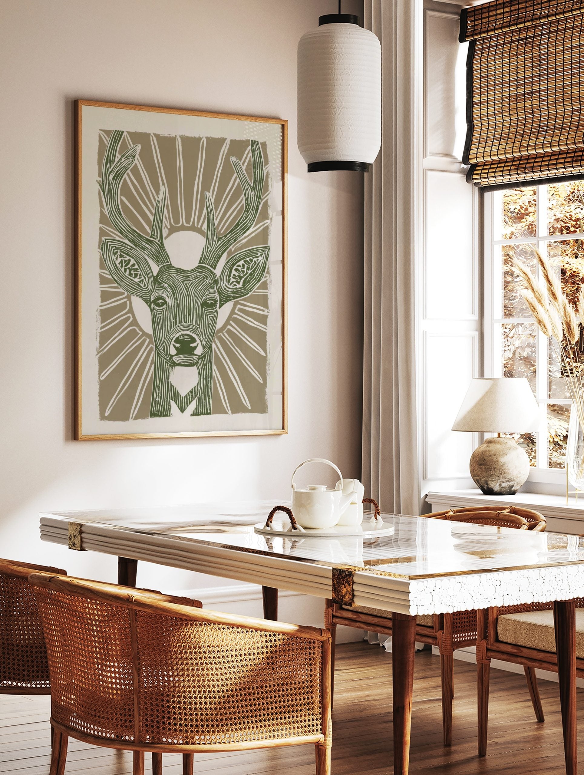 Stylised green deer head with antlers and sunburst on beige background, linocut style animal print, in a styled room mockup