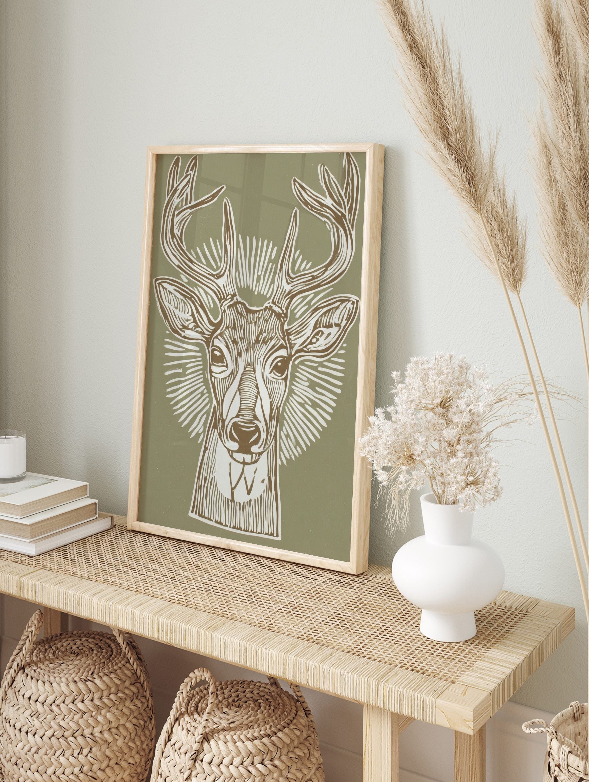Illustrative deer head print with antlers and radial lines on a sage green background, in a, in an alternate framed mockup