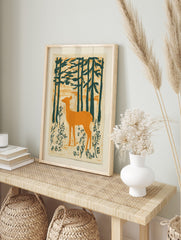 Illustrative print of an orange deer standing in a dark green forest with textured background, in an alternate framed mockup