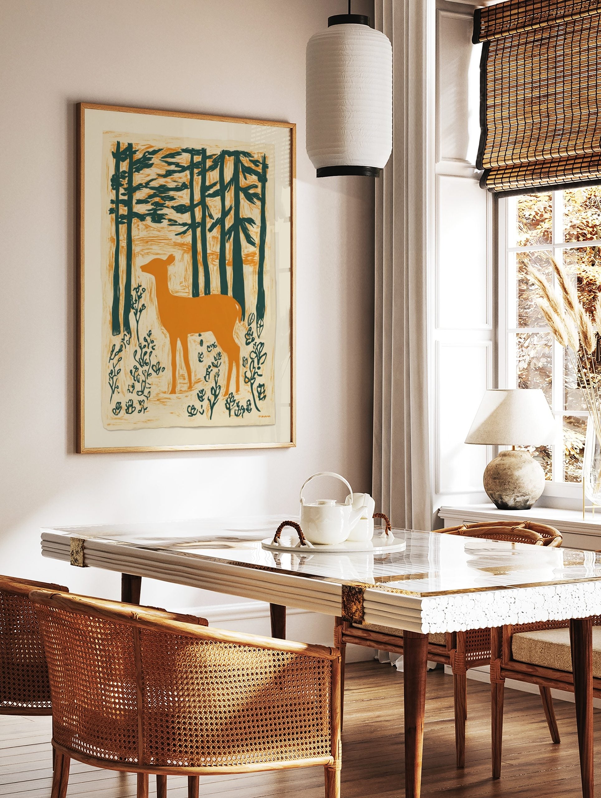 Illustrative print of an orange deer standing in a dark green forest with textured background, in a styled room mockup