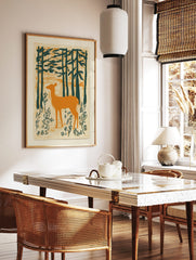 Illustrative print of an orange deer standing in a dark green forest with textured background, in a styled room mockup