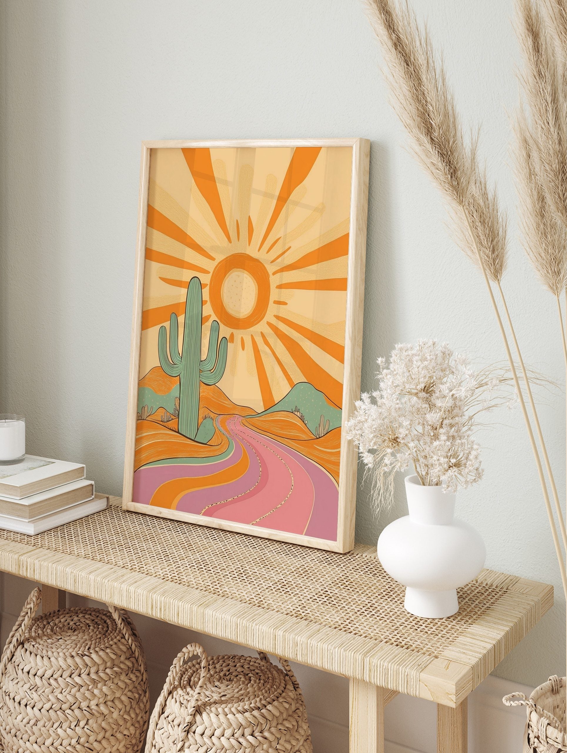 Retro desert landscape art print with a large teal cactus, orange sun, and a winding pink and, in an alternate framed mockup