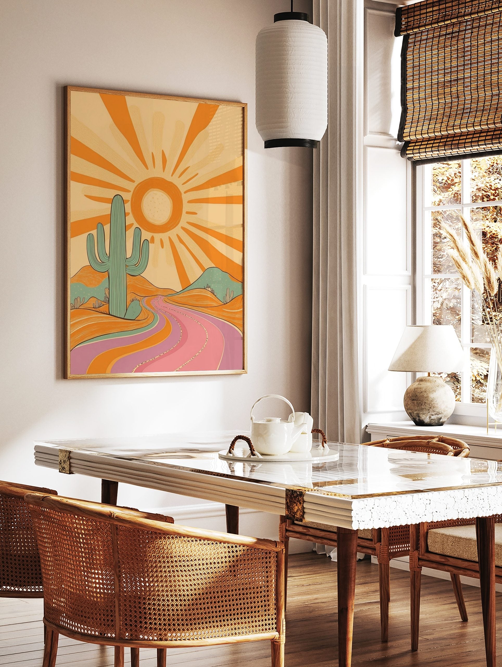 Retro desert landscape art print with a large teal cactus, orange sun, and a winding pink and, in a styled room mockup