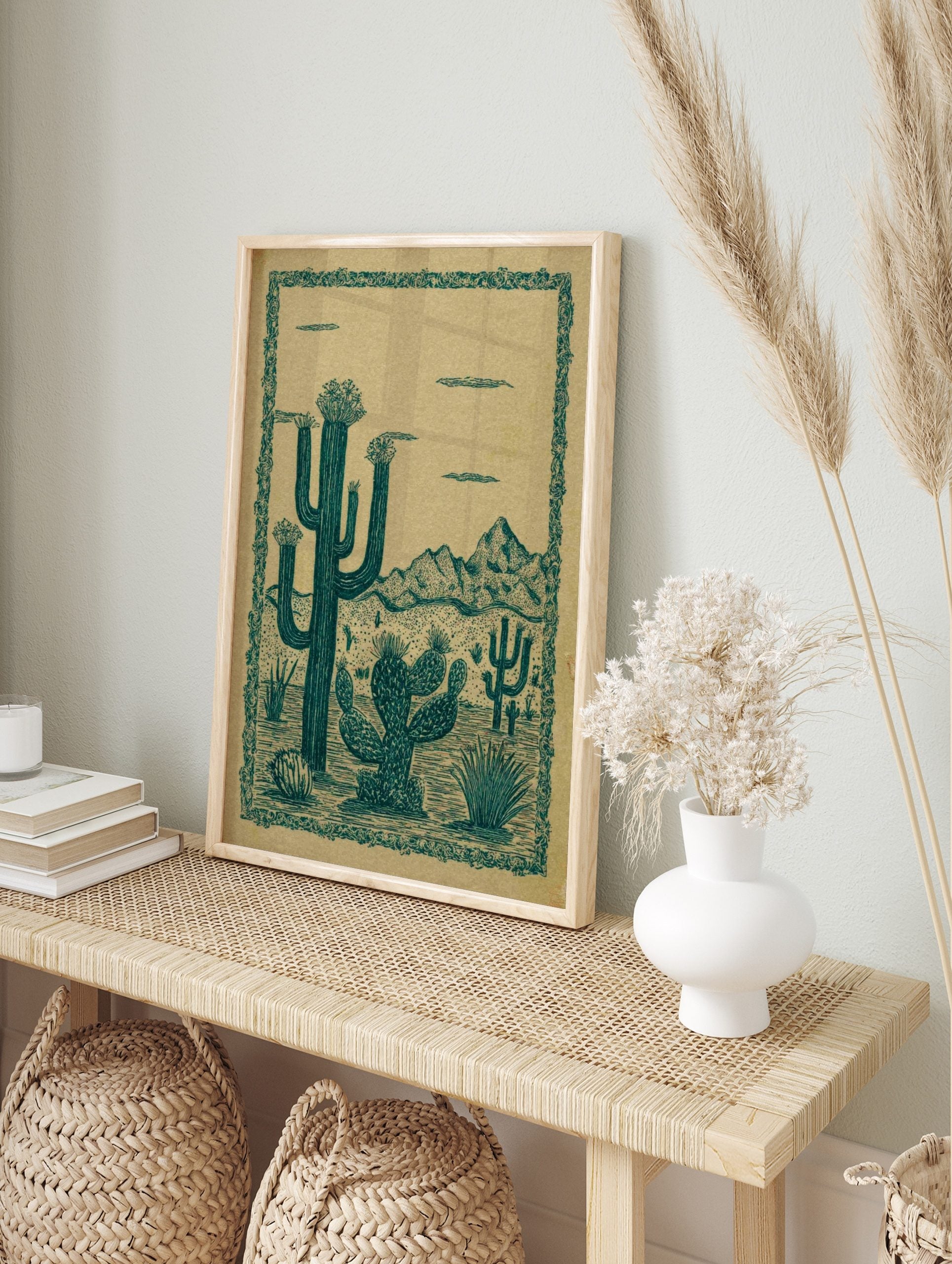 Illustrative desert landscape print with teal green saguaro and prickly pear cacti against a, in an alternate framed mockup