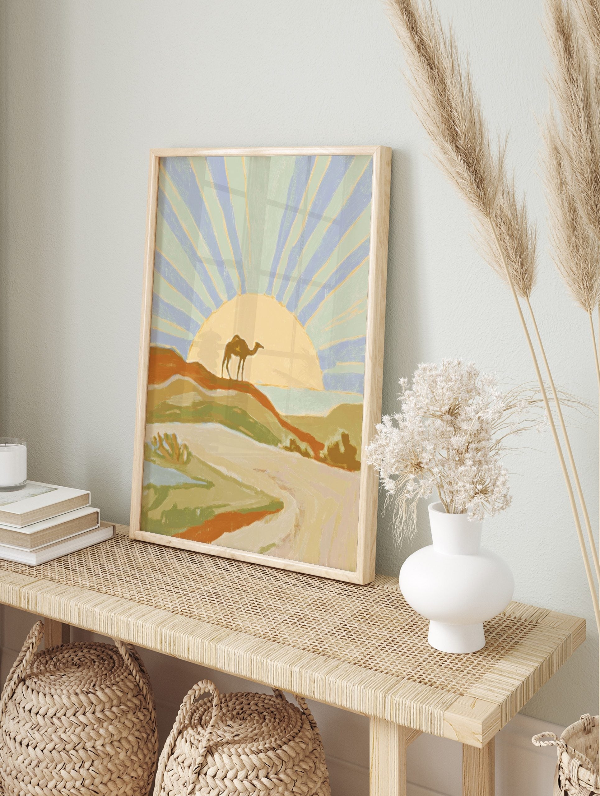 Illustrative desert landscape art print with a camel on a dune, radiating sunset, and distant, in an alternate framed mockup