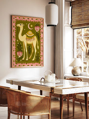 Illustrative camel wall art with ornate saddle, pink border, green background, stylised flowers, in a styled room mockup