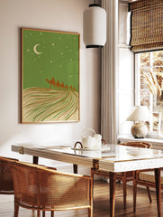 Illustrative desert night scene with camel caravan, crescent moon, and stars against a green sky, in a styled room mockup