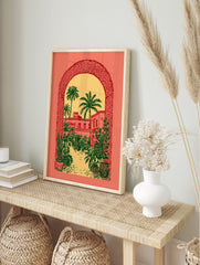 Illustrative print of a desert courtyard with palm trees and buildings, viewed through a, in an alternate framed mockup