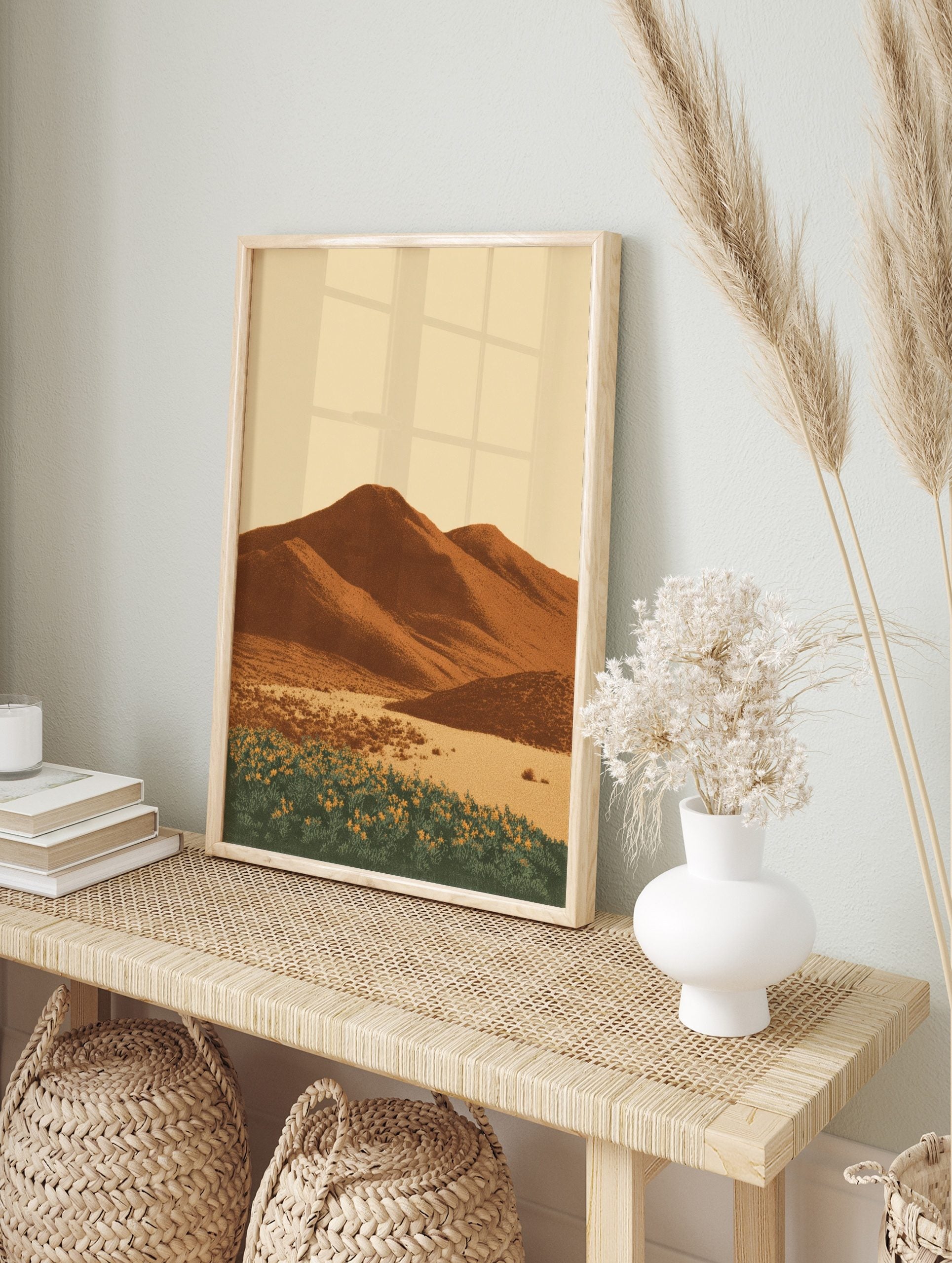 Illustrative desert landscape print with brown mountains, sandy foreground, and yellow flowers, in an alternate framed mockup