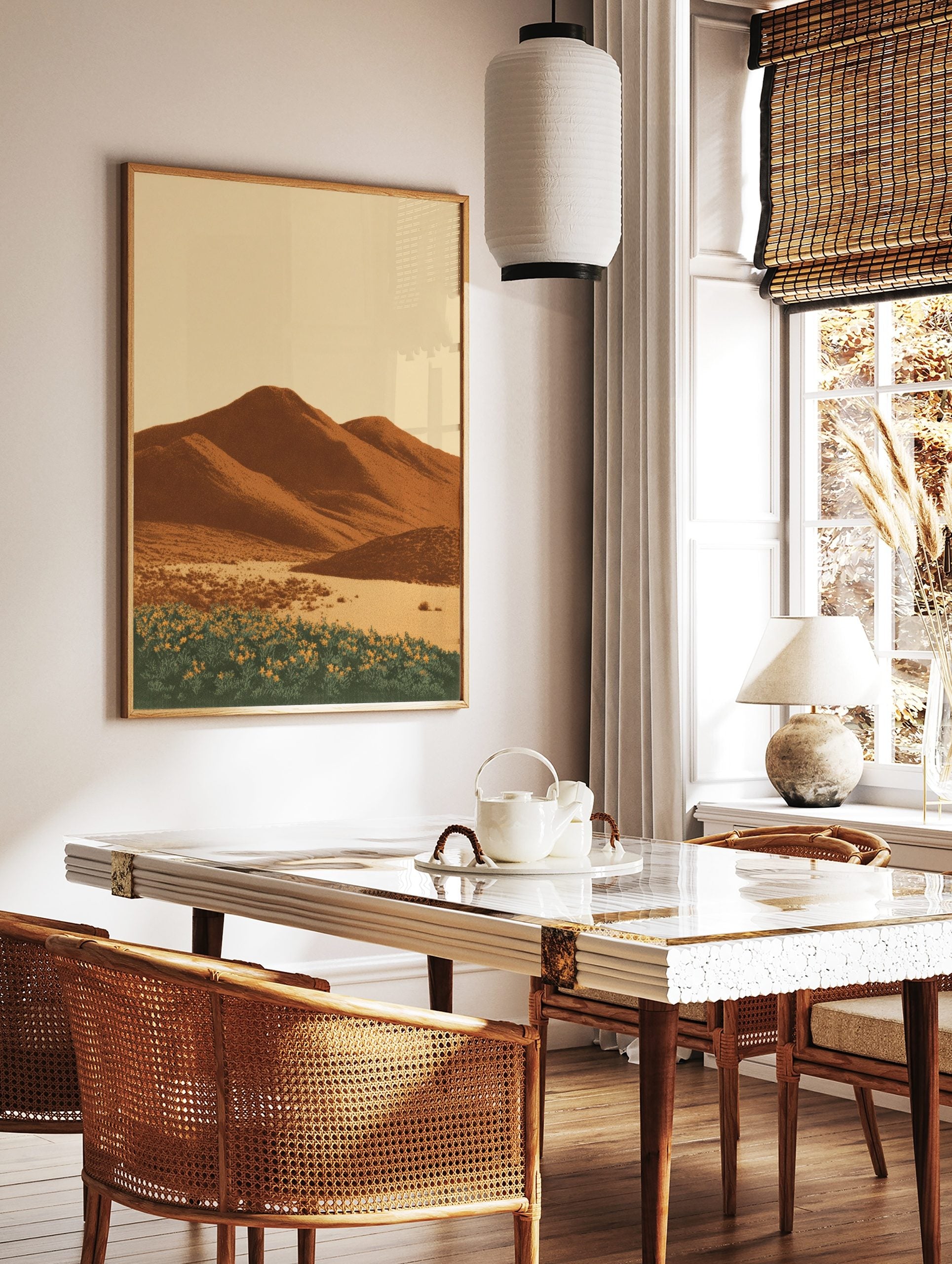 Illustrative desert landscape print with brown mountains, sandy foreground, and yellow flowers, in a styled room mockup