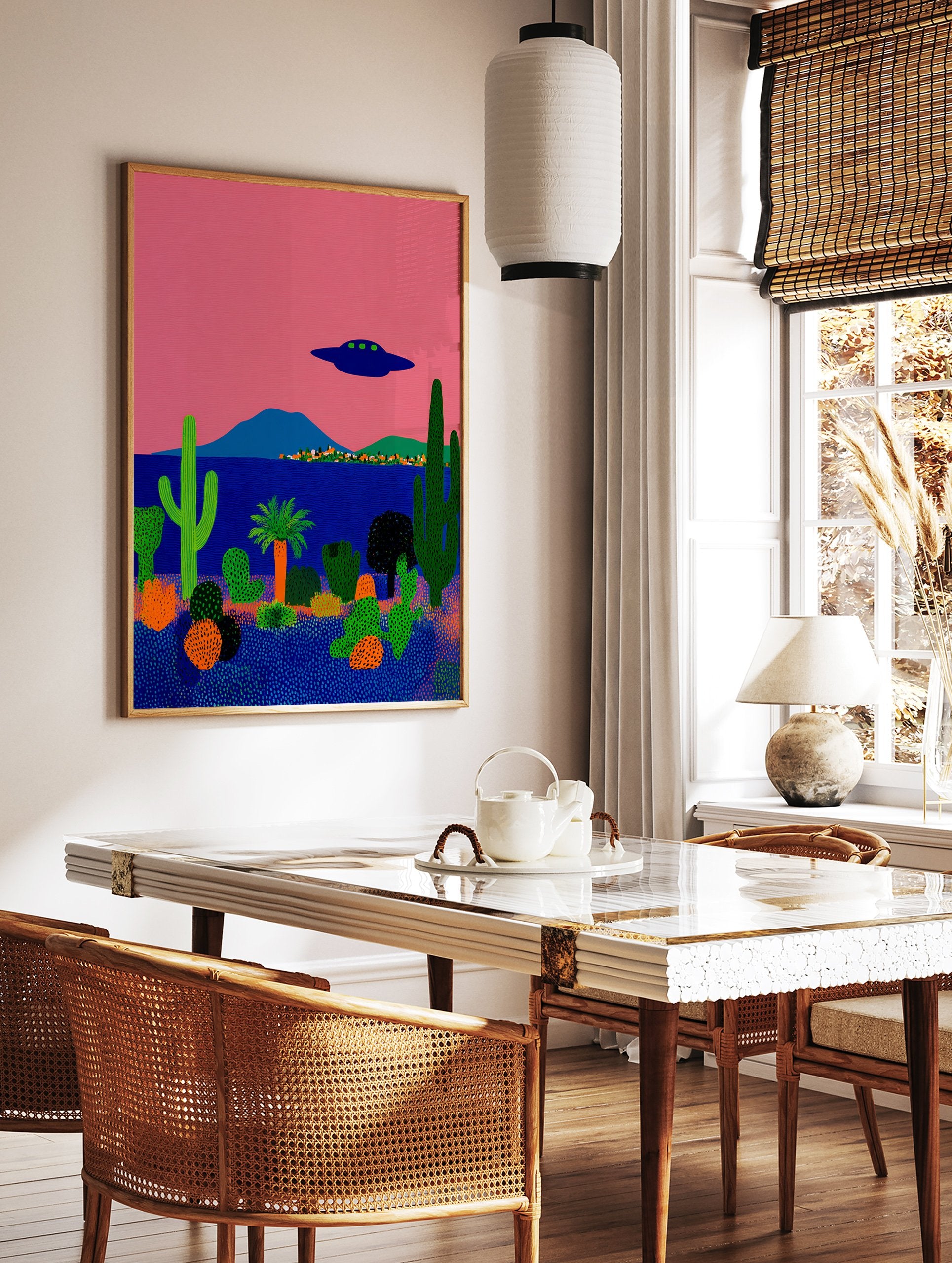 Surreal desert landscape poster with a pink sky, blue ocean, green cacti, and a dark blue UFO flying above a small town. - Image 2