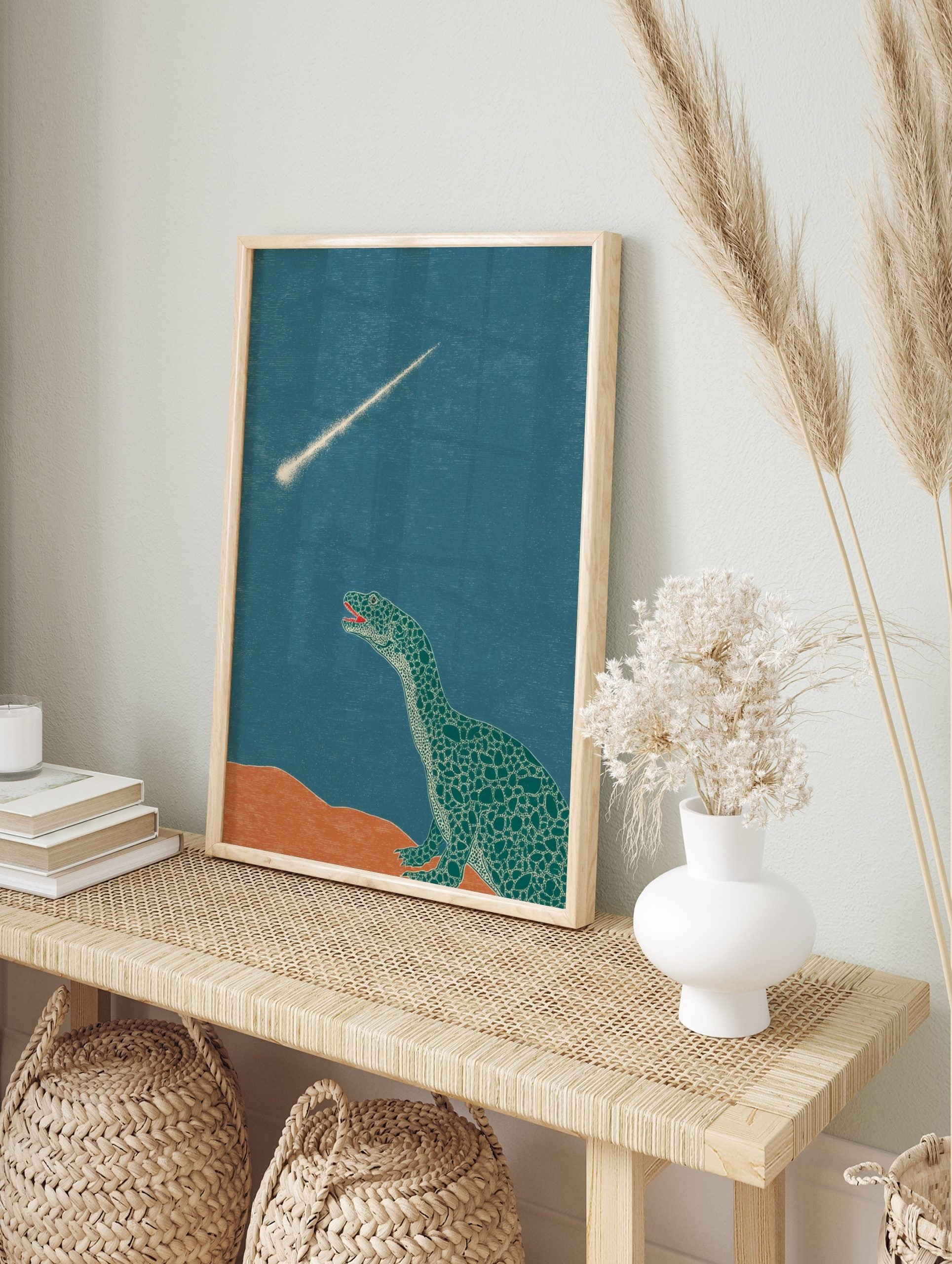 Illustrative dinosaur looking up at a bright meteor streaking across a teal sky with orange, in an alternate framed mockup
