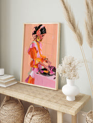 Painterly illustration of a female DJ with headphones and a ruffled orange dress working at a, in an alternate framed mockup