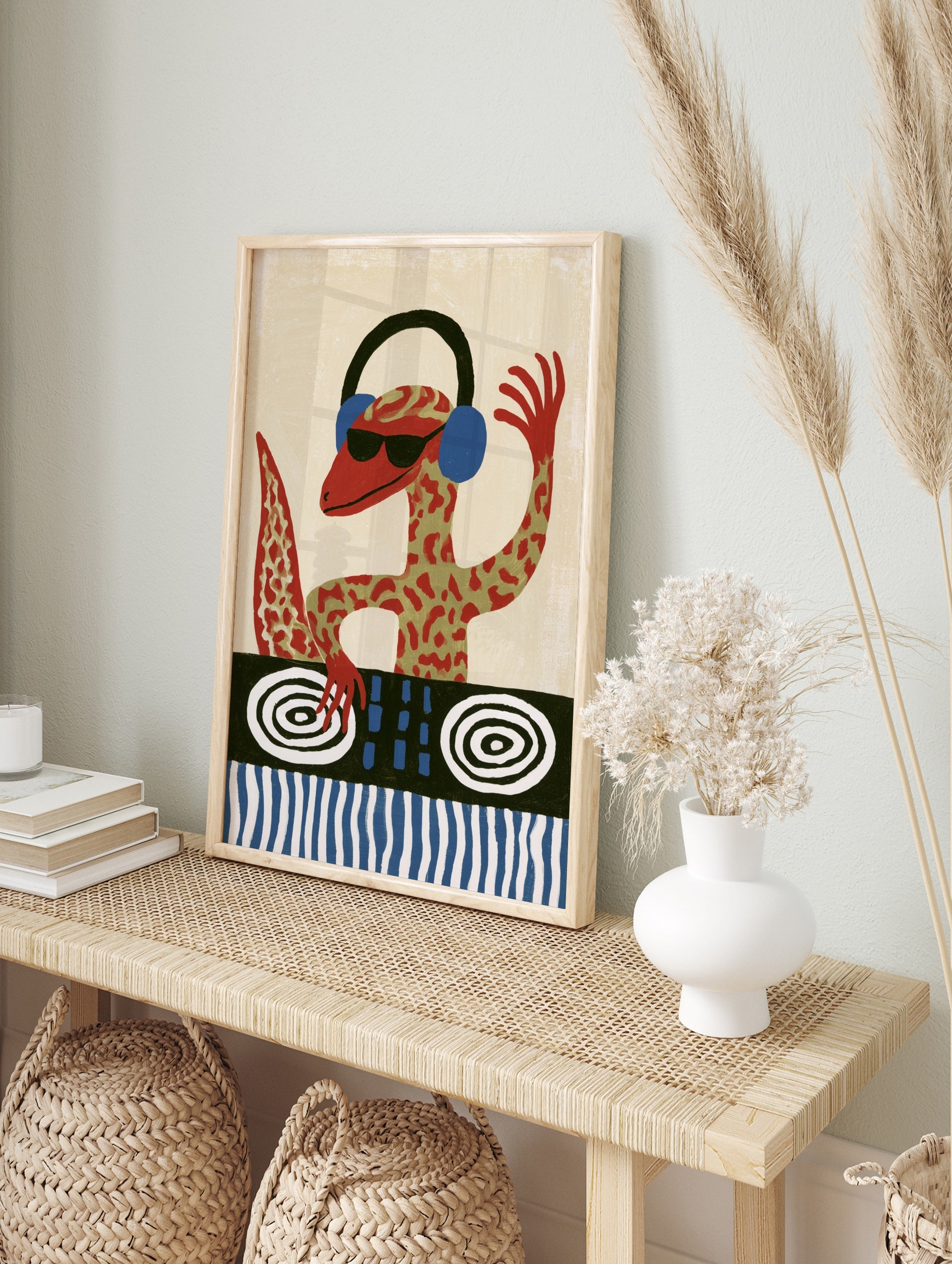 A red gecko DJ wearing headphones and sunglasses at a turntable, illustrative wall art print, in an alternate framed mockup