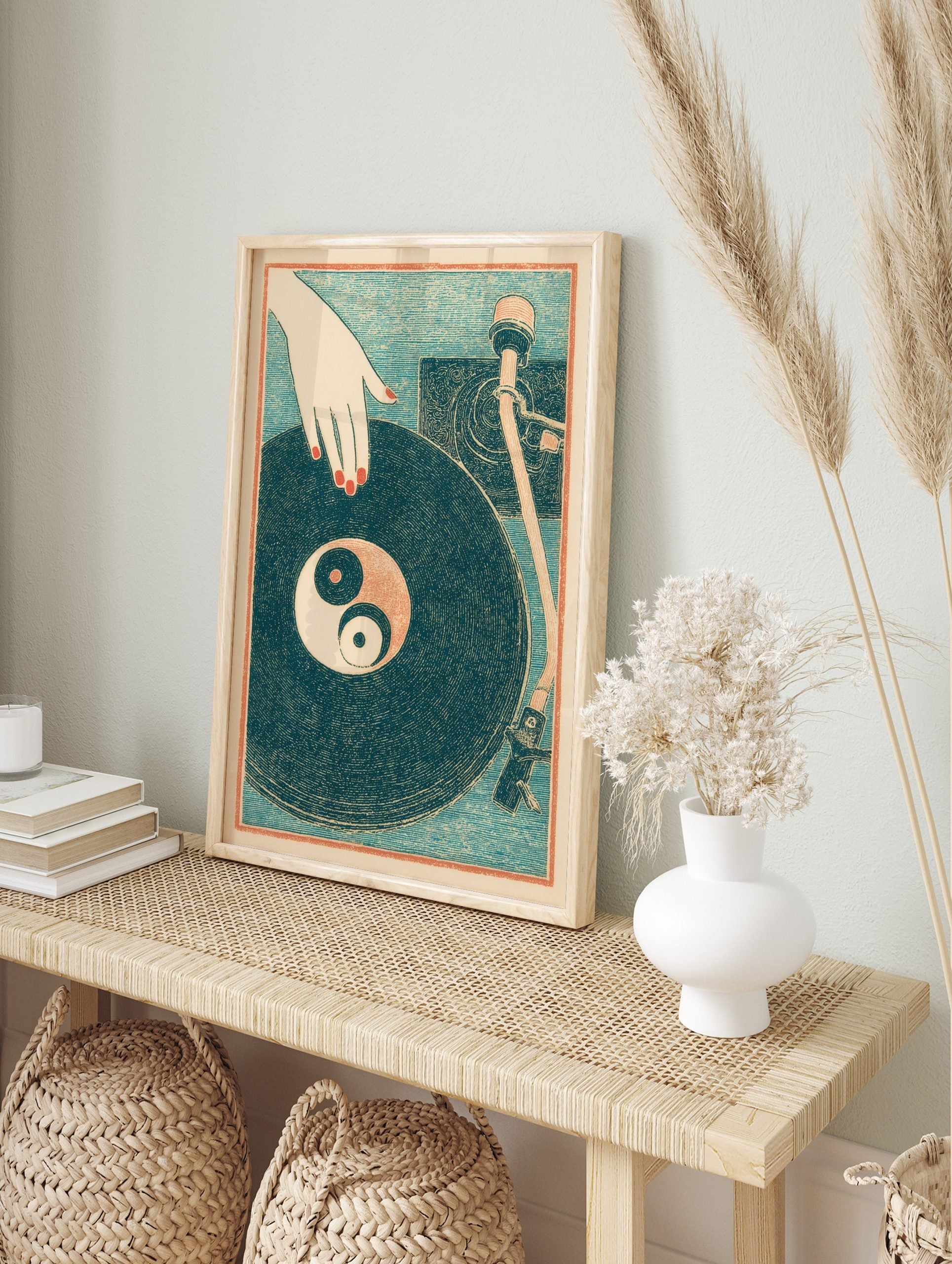 Illustrative print of a hand with red nails over a vinyl record with a Yin Yang symbol on a, in an alternate framed mockup