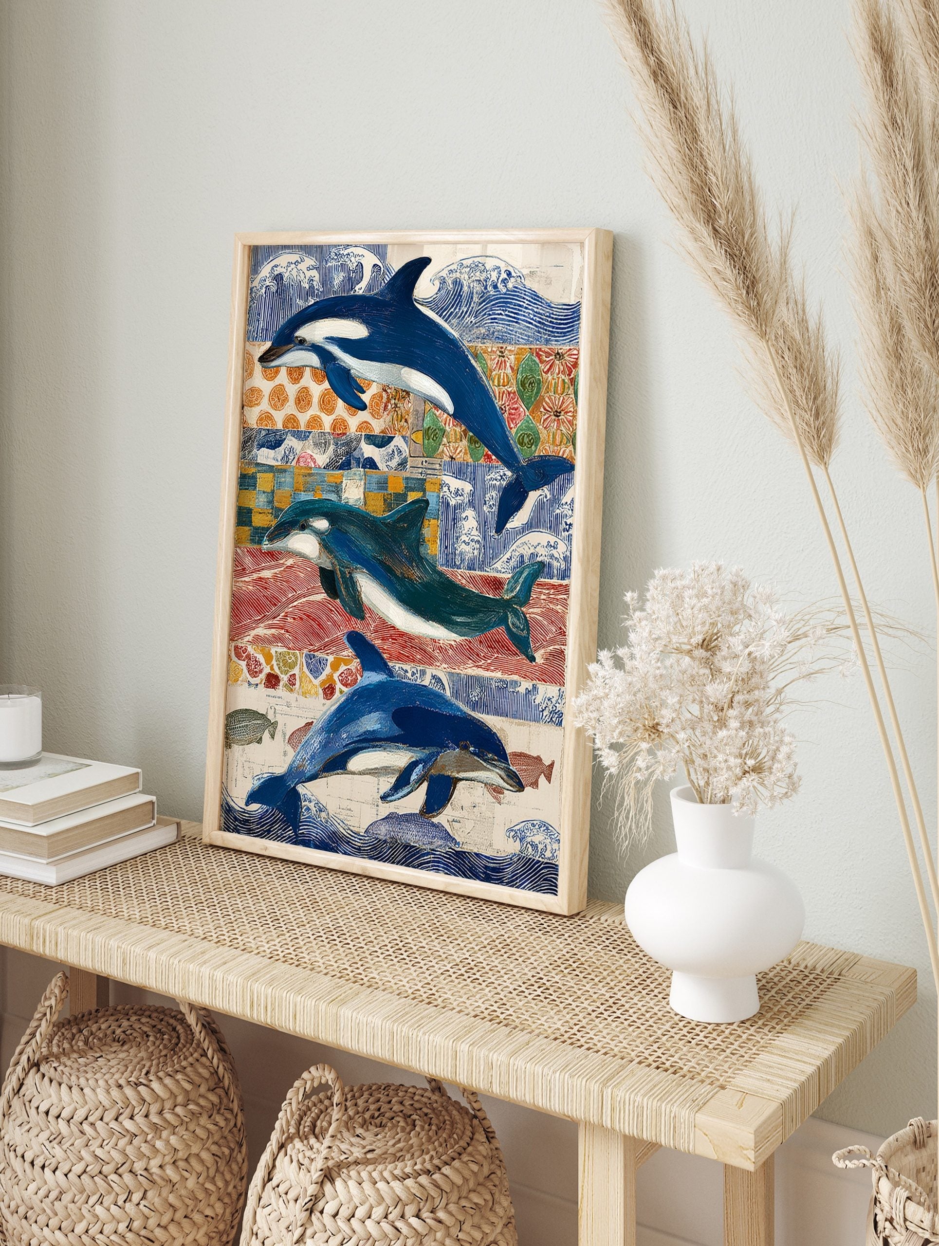 Three blue and white dolphins and orcas swimming against a collage of blue, red, and orange, in an alternate framed mockup