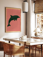 Minimalist dark green dolphin silhouette illustration on a muted pink background, unframed paper, in a styled room mockup
