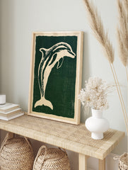 Stylised cream dolphin illustration on a deep green background, illustrative animal wall art, in an alternate framed mockup