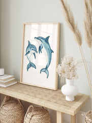 Two blue watercolour dolphins, one large and one small, in dynamic swimming poses on a white, in an alternate framed mockup